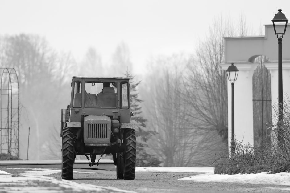A monochrome image of a tractor during a foggy winter morning in rural Latvia.